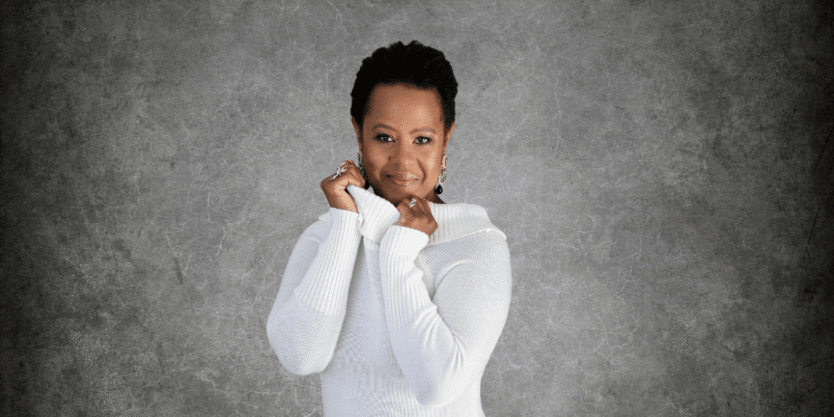 Mag Dalé posing confidently in a white sweater, radiating warmth and strength.