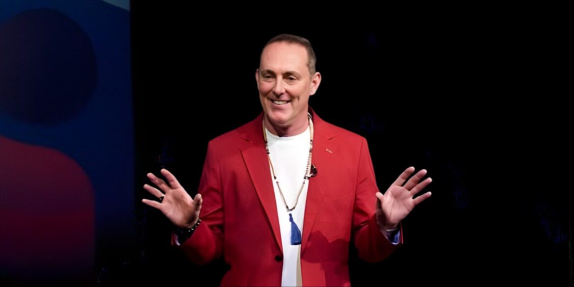 TJ Woodward, in a red blazer, delivering a speech, embodying his Conscious Creation Model to empower intentional living.