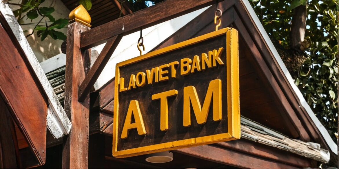an ATM sign from LaoViet Bank, highlighting the importance of avoiding high ATM fees while traveling abroad.