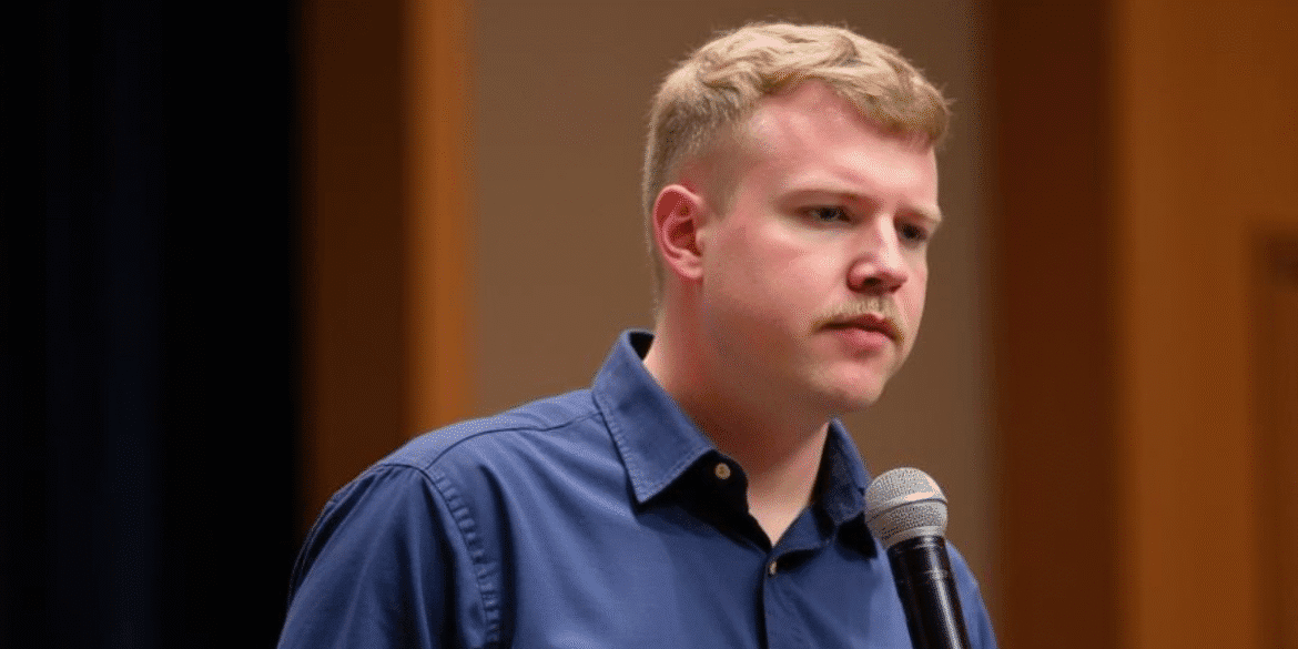 Young man speaking into a microphone during an event or presentation.
