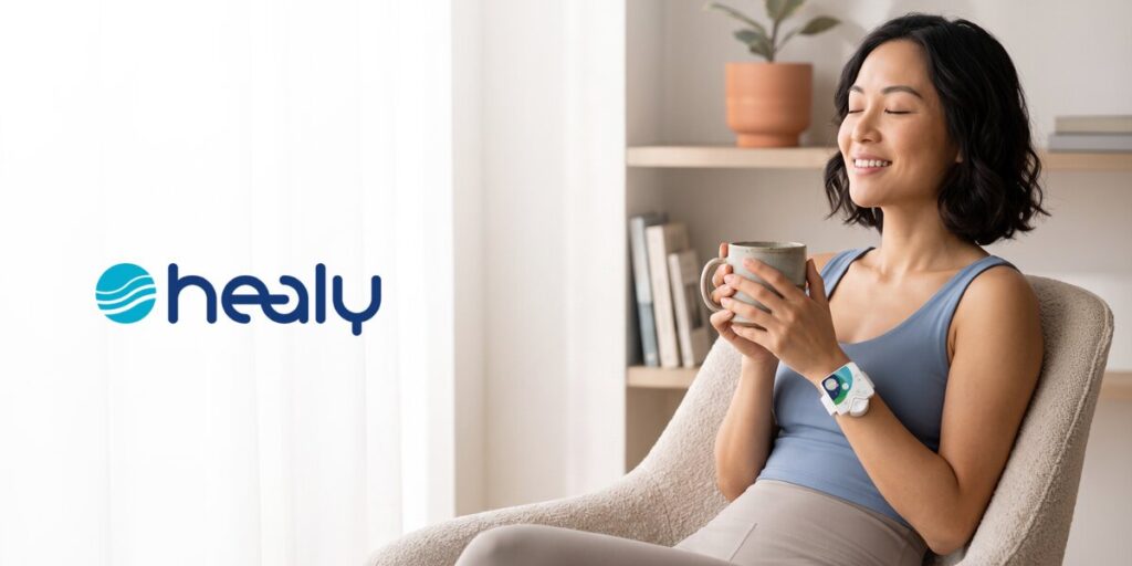 Woman relaxing with a mug while wearing a Healy wellness device on her wrist.